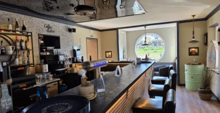 Gemütliche Bar mit langer Theke und schwarzen Stühlen im Bistro Bullauge