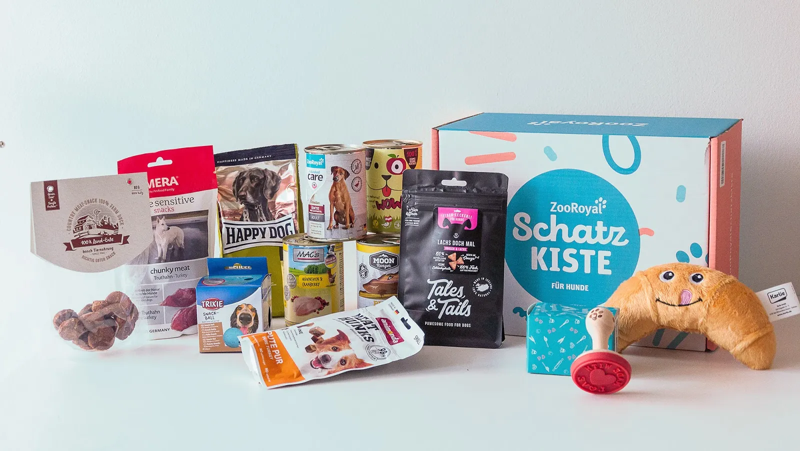 Geöffnete ZooRoyal Schatzkiste mit allen Produkten: Feuchtfutterdosen, Trockenfutter, Hundesnacks und Spielzeug