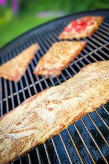 Geräucherter Lachs vom Grill, goldbraun und saftig, garniert mit frischen Kräutern.