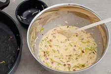 Geriebener Käse und Lauch-Speck-Masse werden zum Ei-Sahne-Guss gegeben