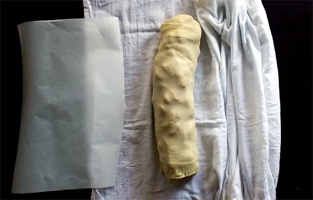 Gerollter Apfelstrudel auf Backpapier, bereit zum Backen, ein Schritt aus Omas Strudel Rezept