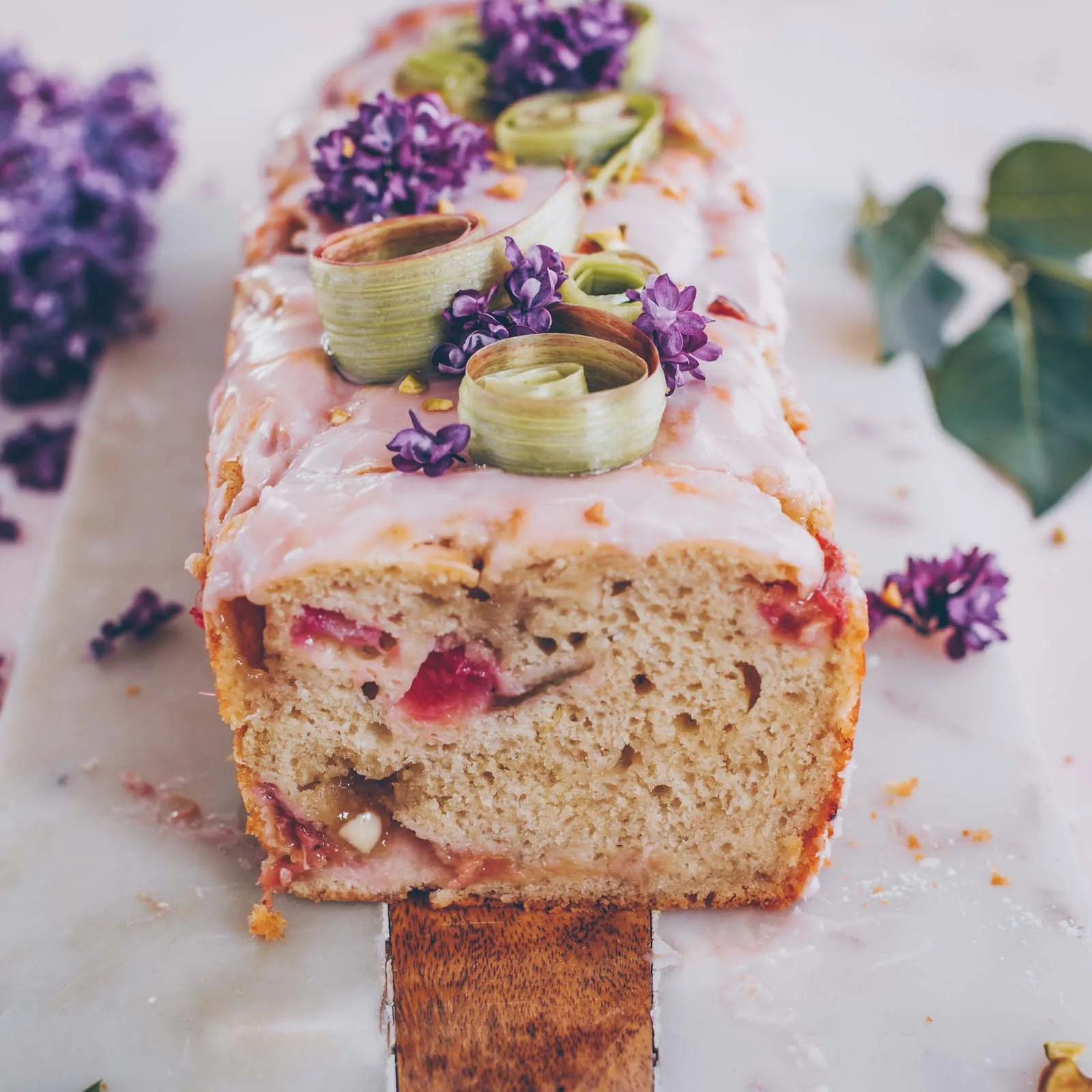 Gesamter veganer Rhabarber-Joghurt-Kuchen in einer Backform auf einem Holzbrett