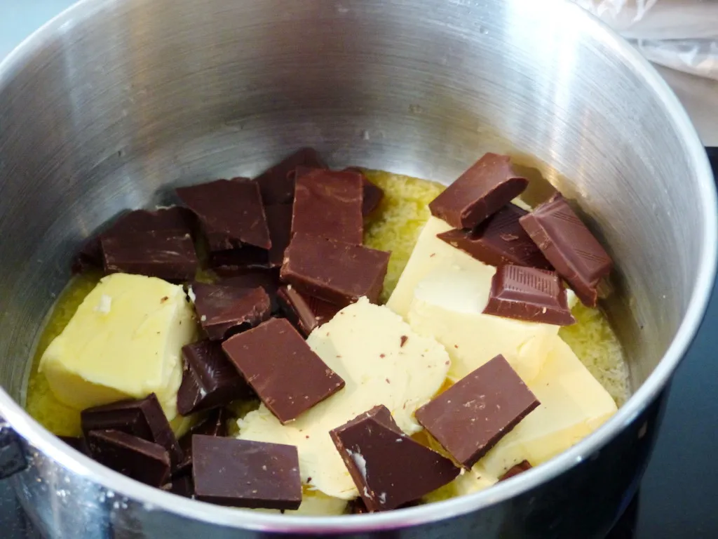 Geschmolzene Butter und dunkle Zartbitterschokolade in einem Topf, bereit für das Kuchenrezept.