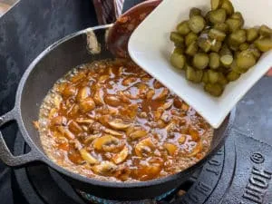 Geschnittene Essiggurken werden dem Boeuf Stroganoff beigefügt für den typischen Geschmack