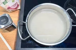 Gewaschener Langkornreis und Salz werden in einem Topf mit Wasser vermischt