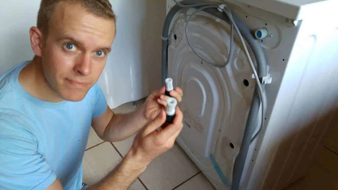 Gewindebolzen der Transportsicherung einer Waschmaschine auf dem Boden neben der Maschine