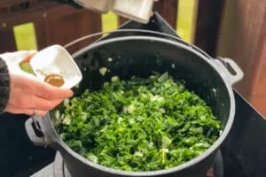 Gewürzter Grünkohl wird im Topf langsam geschmort und umgerührt.