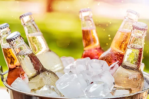 Glasflaschen mit bunten Getränken stehen in einem Eiskübel