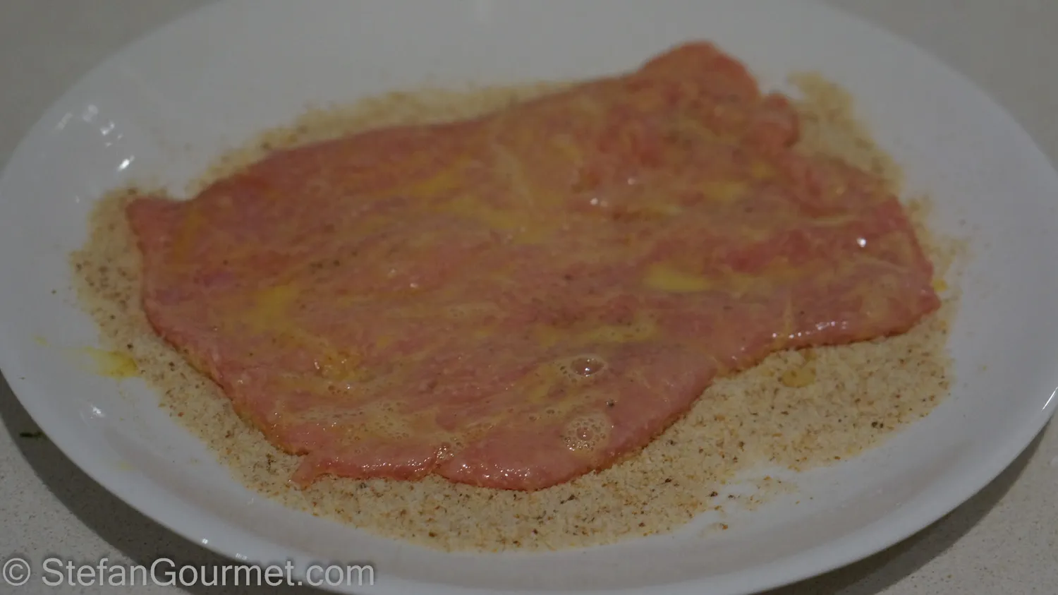 Gleichmäßiges Panieren des Schnitzels mit Semmelbröseln
