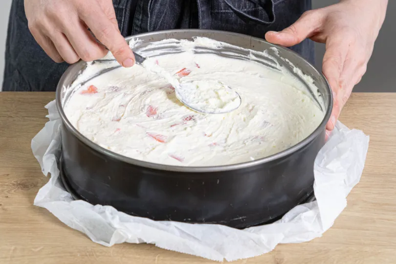 Gleichmäßiges Verstreichen der Erdbeer-Frischkäse-Creme auf dem gekühlten Keksboden.