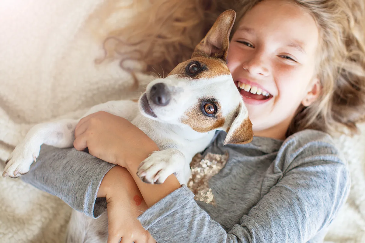 Glückliches Kind mit Hund im Gras – Haustiere mit hohem Aufwand