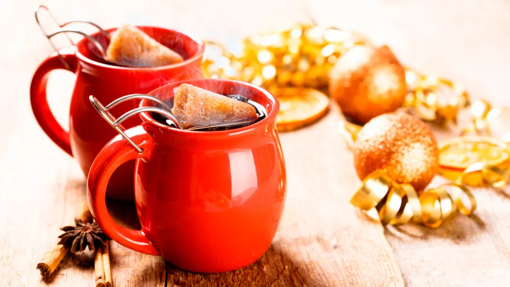 Glühende Feuerzangenbowle in einer großen Schüssel, ein Zuckerhut wird entzündet