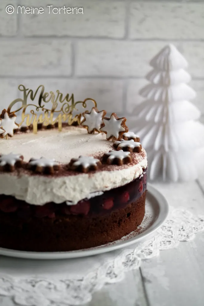 Glühwein Kirsch Torte mit Zimtsternen und Kakaopuder dekoriert, festlicher Kuchen für die Weihnachtszeit.