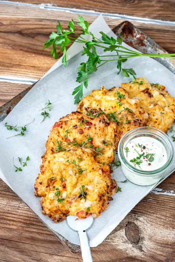 Goldbraun gebackene körniger Frischkäse Taler auf einem Backblech, bereit zum Servieren mit frischem Kräuterdip.