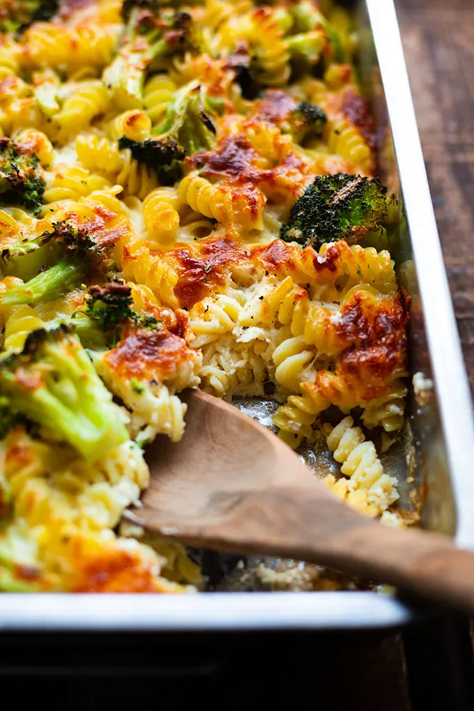 Goldbraun gebackener Brokkoli-Nudelauflauf mit Sahnesauce in einer rustikalen Auflaufform auf dunklem Holztisch.