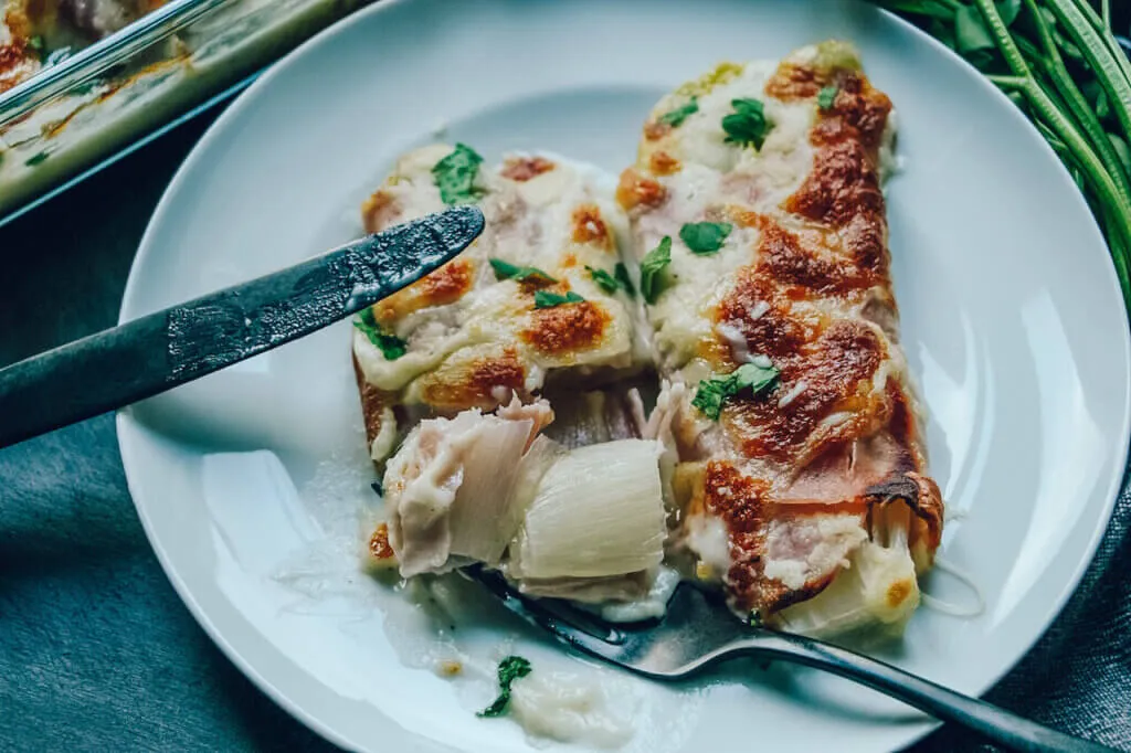 Goldbraun gebackener Chicoree Auflauf mit geschmolzenem Mozzarella und frischer Petersilie.