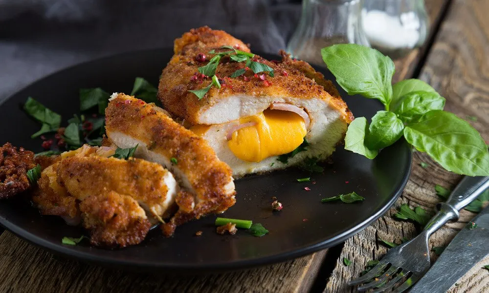 Goldbraun gebratenes Cordon Bleu in einer Pfanne mit Butterschmalz, bereit zum Servieren