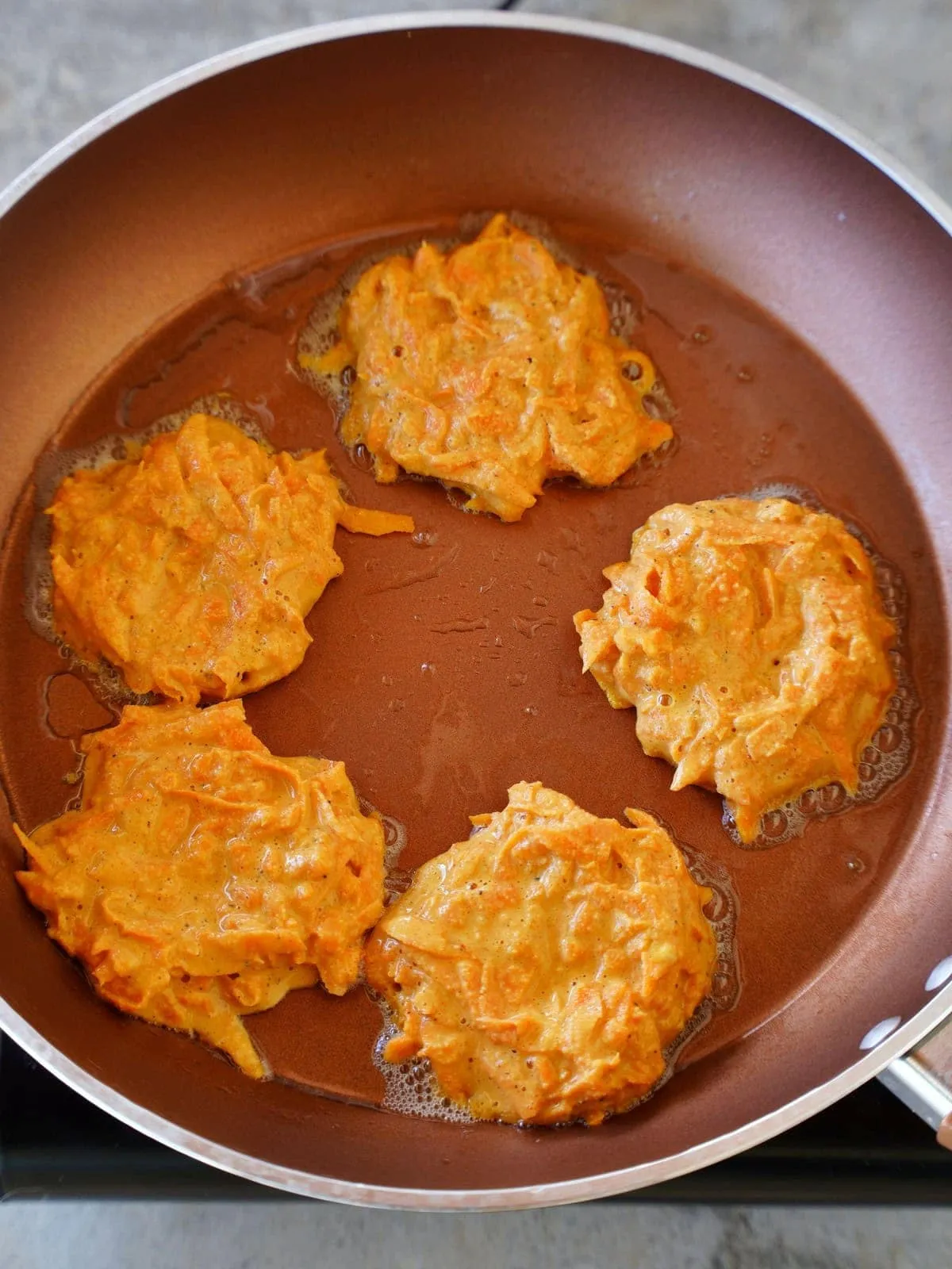 Goldbraune Karotten-Bratlinge werden in einer Pfanne mit Öl gebraten