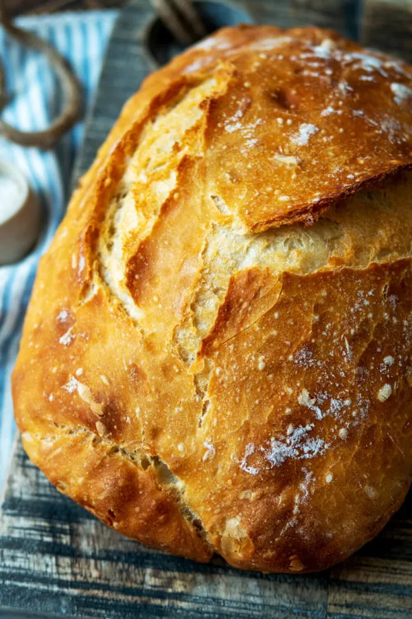 Goldbraunes, selbst gebackenes Brot auf einem rustikalen Holzbrett, zeigend die knusprige Oberfläche