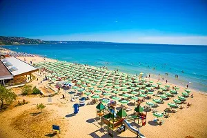 Goldstrand in Bulgarien mit breitem Sandstrand und sonnenbadenenden Menschen, perfekt für warme Badeferien im Juli.