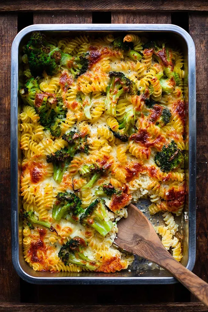 Große Auflaufform mit dem gebackenen Brokkoli-Nudelauflauf und einem Servierlöffel, bereit zum Portionieren für die ganze Familie.