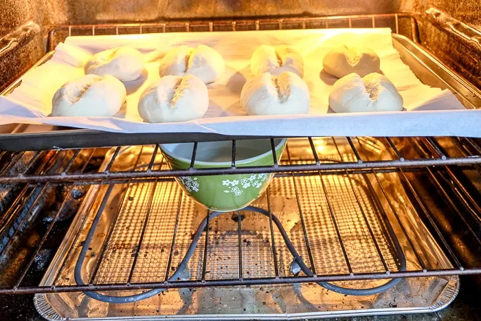 Grüne Schüssel mit Wasser im Ofen unter backenden Brötchen