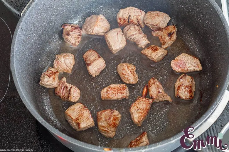 Gulaschfleisch wird in kleinen Mengen in einem Bräter scharf angebraten, um Röstaromen für das perfekte Gulasch Rezept zu entwickeln.