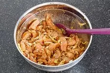 Gyrosfleisch und Zwiebeln werden in einer Schüssel mit der würzigen Marinade vermengt