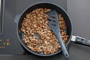 Hackfleisch wird in einer großen Pfanne scharf angebraten, eine essentielle Zutat für die herzhafte Taco-Füllung.