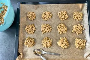 Haferkeksmasse mit einem Teelöffel auf einem Backblech mit Backpapier verteilen