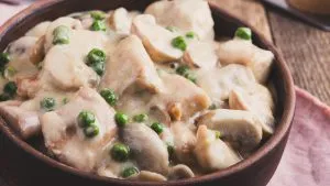 Hähnchen-Jägerpfanne mit Pilzen und Erbsen in einer rustikalen Schüssel