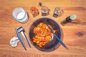 Hähnchenstreifen werden in einer Schüssel mit einer würzigen Marinade aus Olivenöl, Paprika, Kreuzkümmel und Knoblauch vermischt