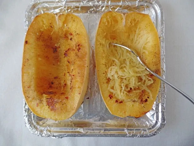 Hälften von Spaghettikürbis auf einem mit Folie bedeckten Backblech