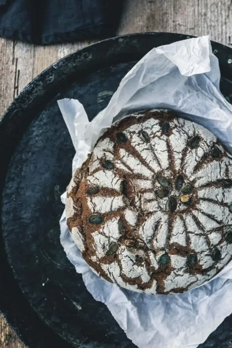 Hand mit einem Stück Sauerteigbrot mit goldbrauner Kruste, bereit zum Belegen
