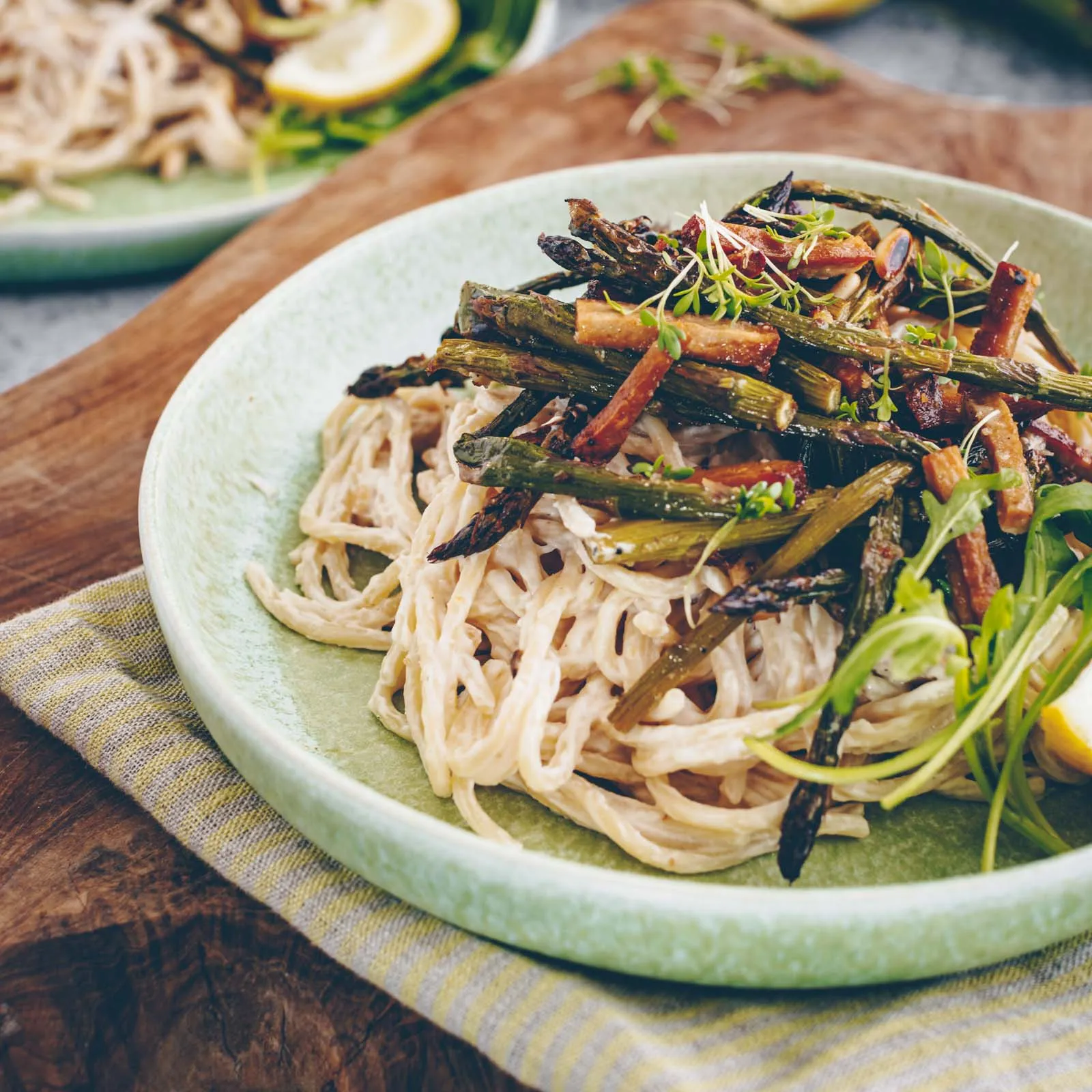 Hand rührt cremige Spargel-Pasta in einer großen Pfanne, bereit zum Servieren