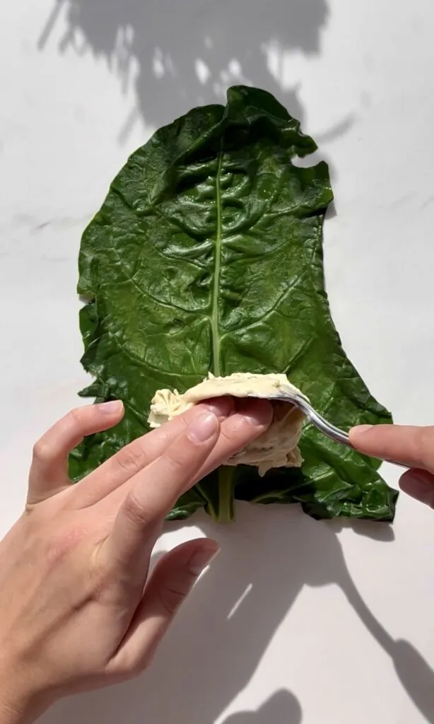 Hände beim Wickeln der Capuns in die blanchierten Mangoldblätter.