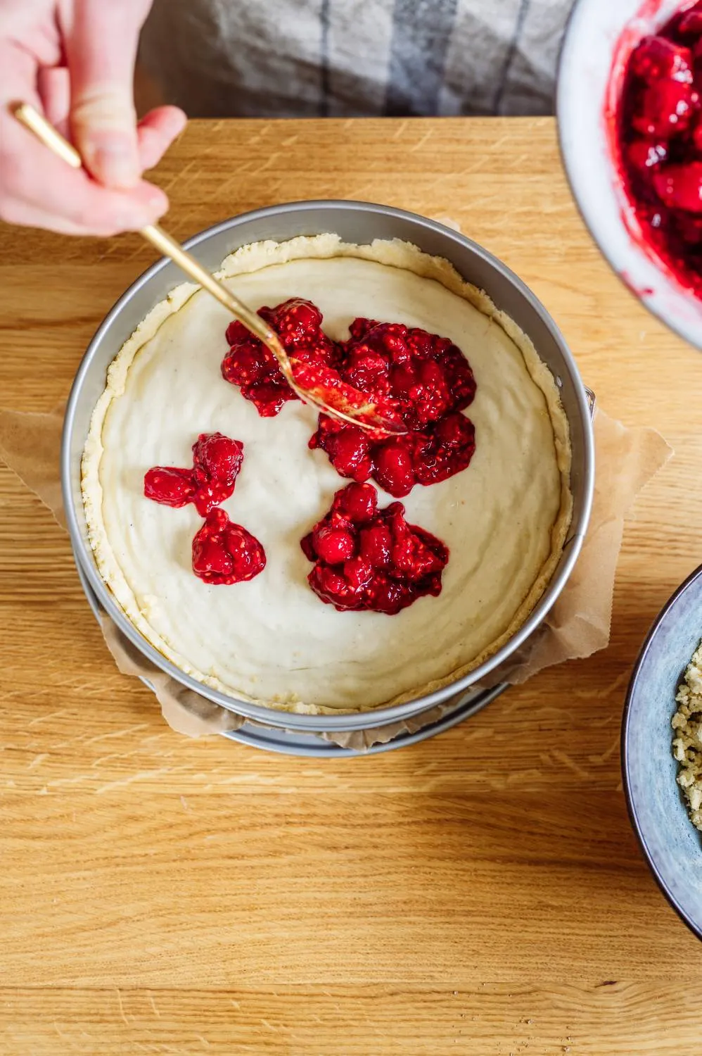 Hände drücken den Streuselteig als Boden und Rand in die Springform für einen festlichen Geburtstagskuchen