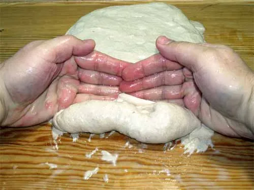 Hände formen längliche Seelen-Teiglinge auf der Arbeitsfläche