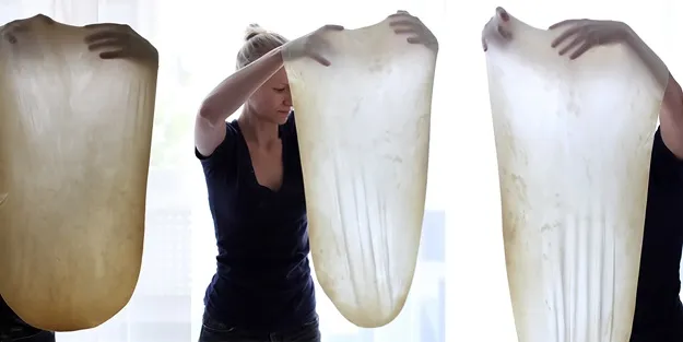 Hände ziehen Strudelteig hauchdünn aus, eine detaillierte Anleitung für perfektes Strudel Rezept