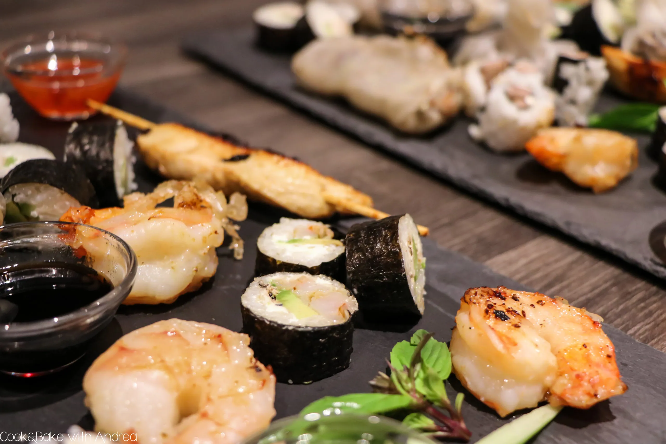 Hausgemachte Sushi-Variationen, bestehend aus Maki und Inside-Out-Rolls mit Gurke, Avocado und Garnelen, präsentiert als exquisite asiatische Vorspeise.