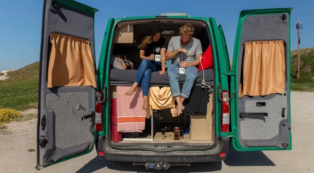 Heidi und Christian bereiten mit der AeroPress, einer Reise Kaffeemaschine, frischen Kaffee im Auto zu. Ideale Kaffeezubereitung für unterwegs.