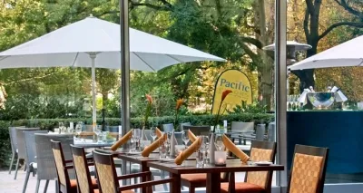 Helles Pacific Colors Restaurant im Hilton Frankfurt mit bodentiefen Fenstern und Blick auf den Park, ideal für internationale und lokale Küche vor oder nach dem Opernbesuch.