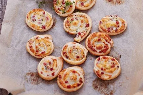 Herzhafte Blätterteig-Schnecken gefüllt mit Raclettekäse und Schinken, perfekt als Snack oder Beilage.