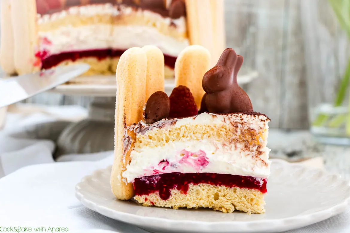 Himbeer-Sahne-Torte zu Ostern, festlich dekoriert mit frischen Himbeeren, Schokohasen und Löffelbiskuit. Eine perfekte sahnetorte für Ihre Ostertafel.