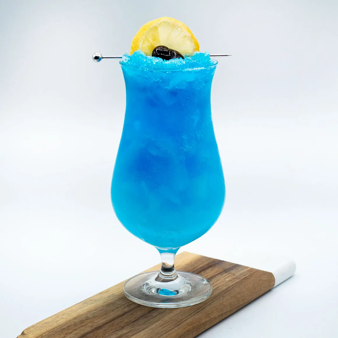 Himmelblauer Blue Lagoon Cocktail mit Zitronenscheibe und Kirsche