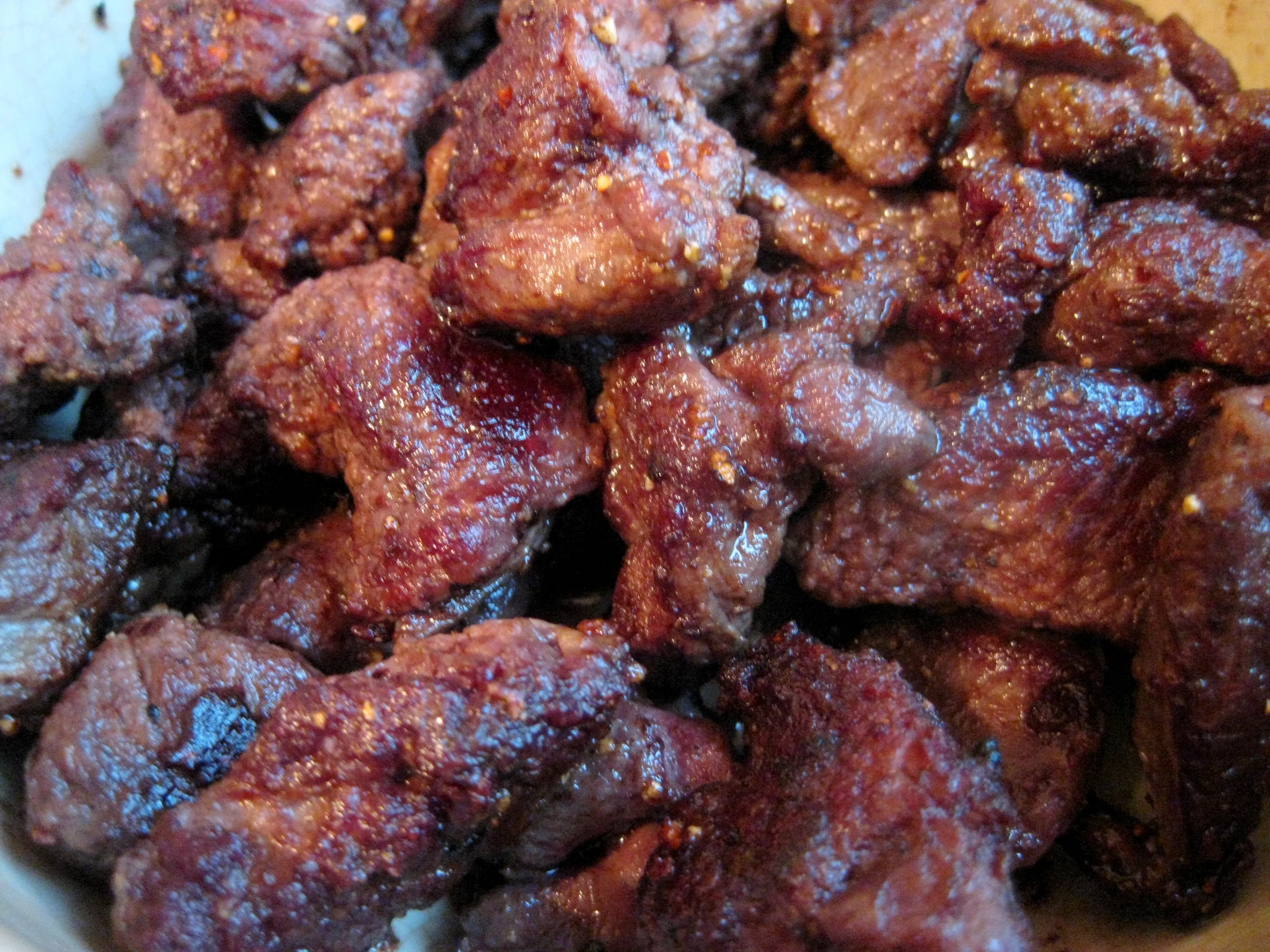 Hirschfleischwürfel werden in einem Topf mit heißem Öl angebraten. Das Fleisch ist bereits leicht gebräunt.