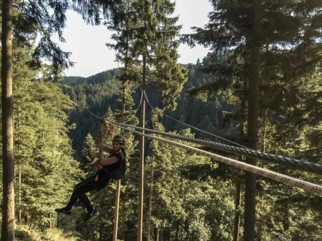 Hirschgrund Zipline im Schwarzwald mit Person, die an einem Stahlseil durch den Wald saust