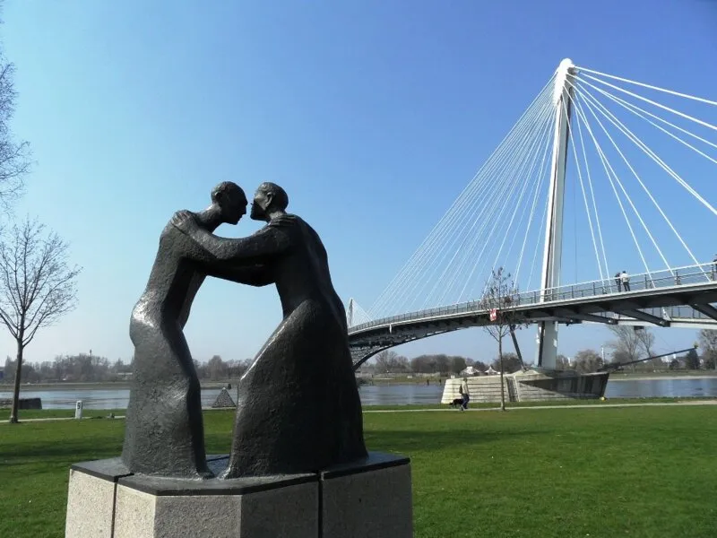 Historische Brücke mit klassischer Statue über den Rhein, symbolisch für die reiche Geschichte der Region