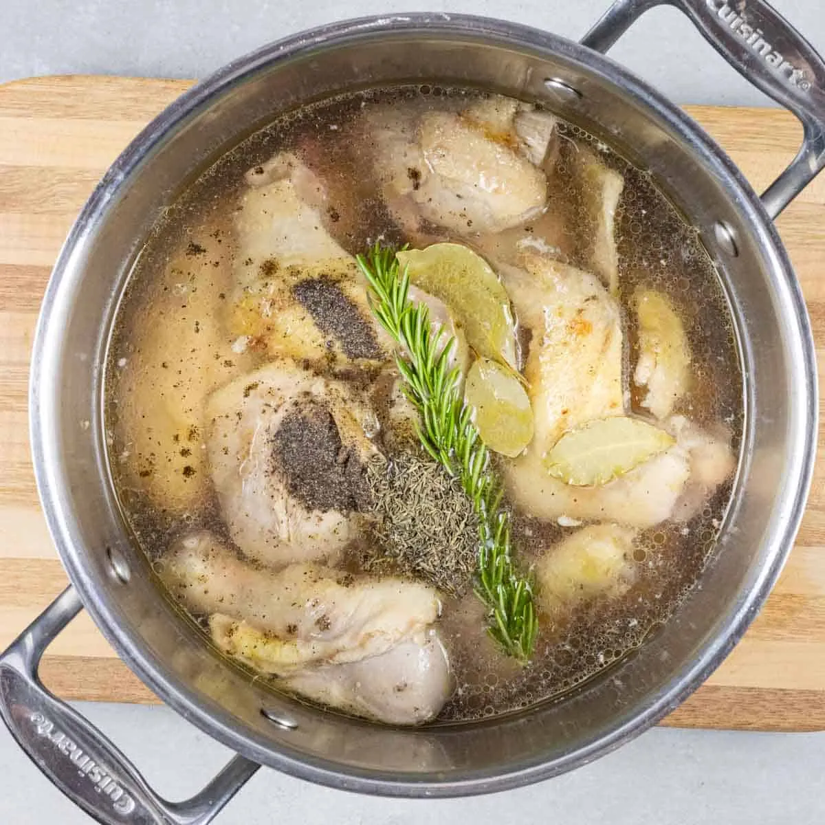 Huhn, Kräuter und Brühe im Suppentopf zum Köcheln für spanische Suppe.