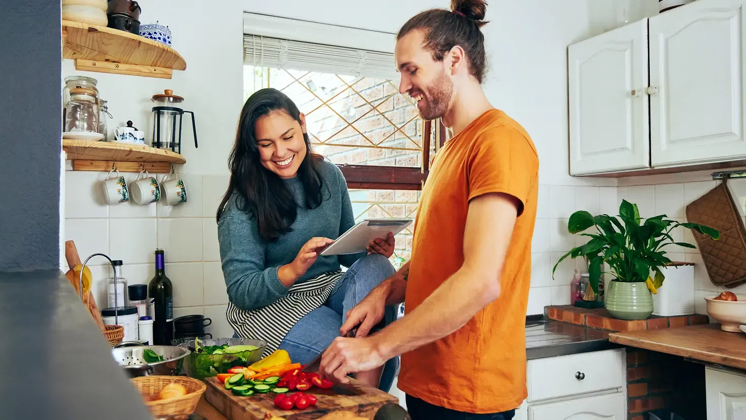 Junges Paar bereitet gesunde Mahlzeit mit viel Obst und Gemüse zu, um nachhaltig abzunehmen